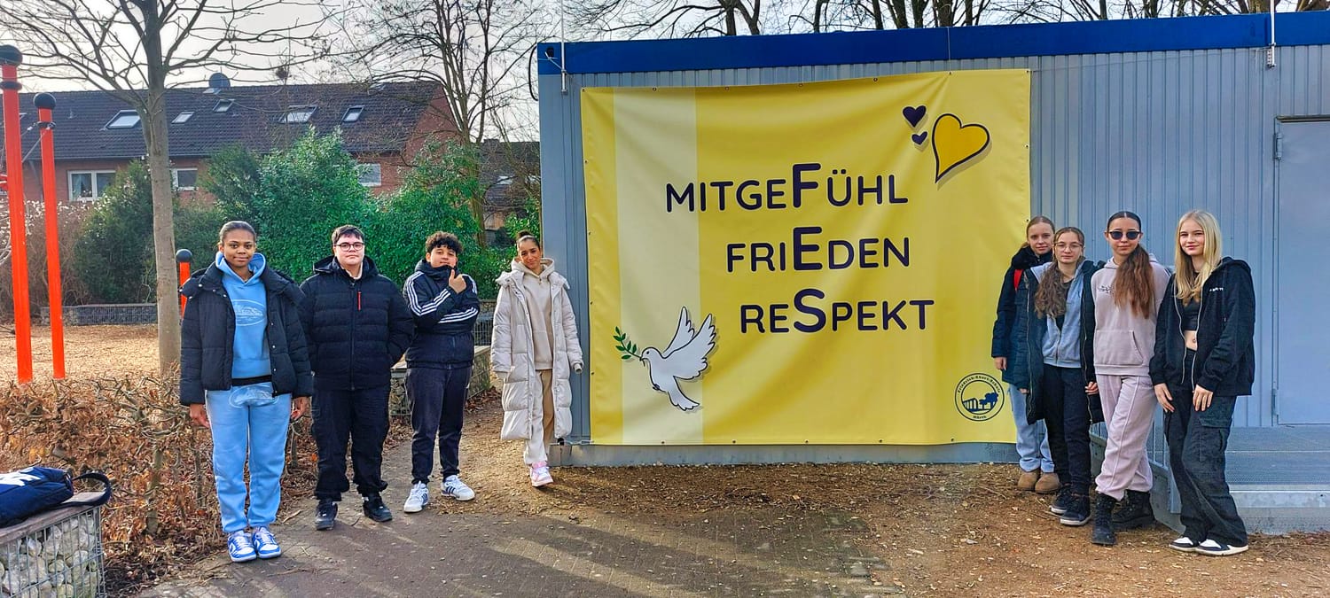 Neues Schul-Banner „MITGEFÜHL - FRIEDEN - RESPEKT“ der Friedrich-Ebert Realschule Hürth wird von Schüler:innen präsentiert.
